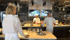 Chef John Stephano wears a headset in the Culinary Arts Kitchen aboard Seven Seas Grandeur so his comments are easily heard by all 18 students.