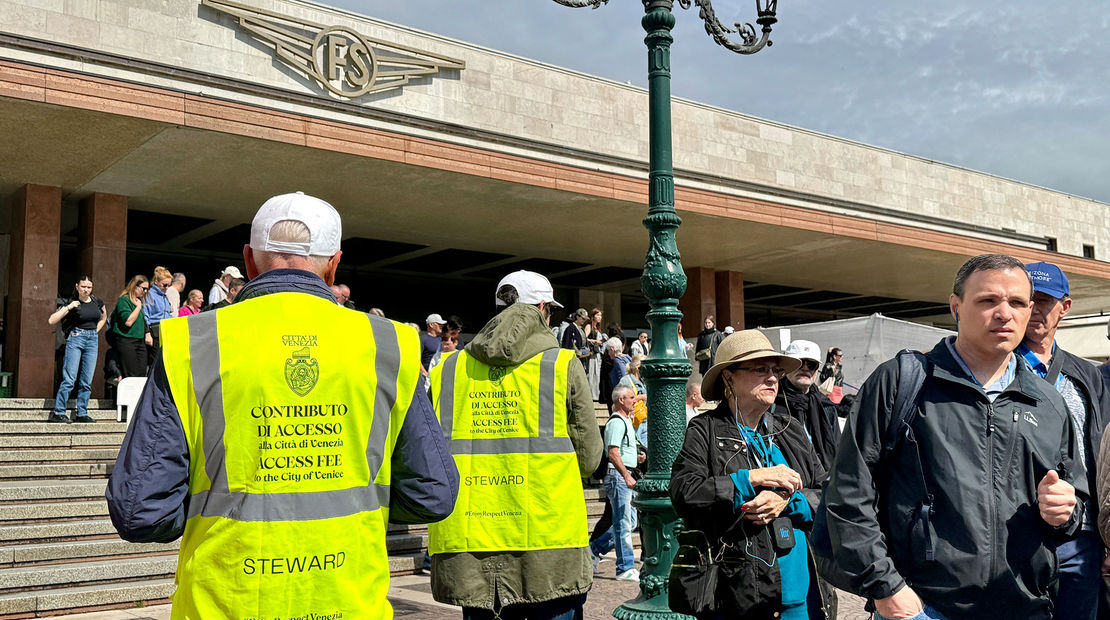 Venice municipal workers in reflective vests outside of the Venezia Santa Lucia train station to assist visitors with a new entrance fee that day-trippers must pay.