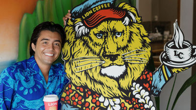 Lion Coffee tour guide Makana David stands next to the company’s familiar lion character.