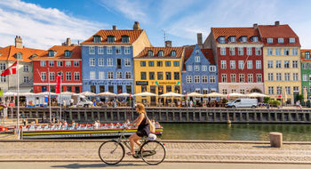 A sightseeing boat sails along Copenhagen's colorful Nyhavn waterfront.