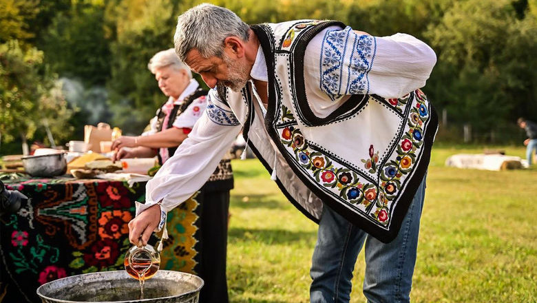 A man in folkloric costume cooks traditional food in Neamt County, Romania.