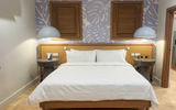 The property's beachfront one-bedroom villa suite accommodations feature a king bed with a rattan headboard.